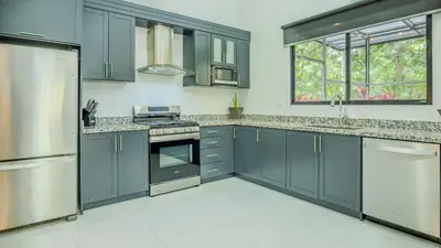 a kitchen with stainless steel appliances and gray cabinets at Modern Retreat in the Rainforest with River Access in Ojochal
