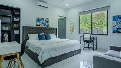 a bedroom with a bed and a desk and a chair at Modern Retreat in the Rainforest with River Access in Ojochal