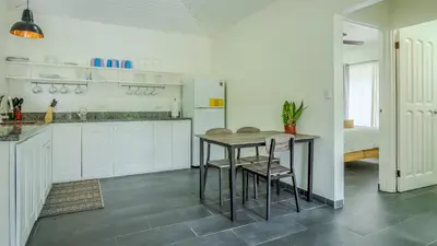 a kitchen with white cabinets and a table and chairs at Tropical 3 Cozy Cabins with Pool in Central Uvita in Uvita