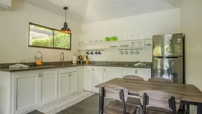 a kitchen with a wooden table and a refrigerator at Tropical 3 Cozy Cabins with Pool in Central Uvita in Uvita