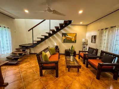 a living room with couches and a staircase at Rustic Tropical Retreat with Pool & Garden Ojochal in Ojochal