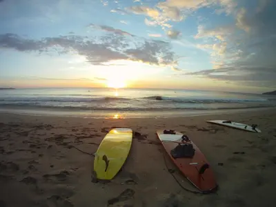 two surfboards sitting on the beach with the sunset at Casa Rustica 1 in Playa Grande