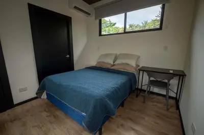 a small bedroom with a bed and a table at Casa Playa Avellanas in Playa Avellana
