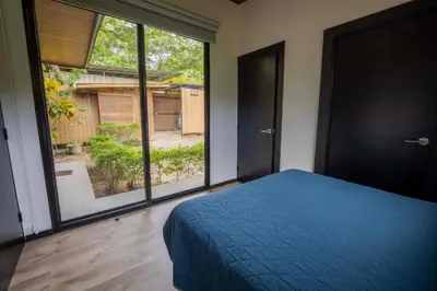 a bedroom with a blue bed and a large window at Casa Playa Avellanas in Playa Avellana