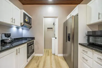 a kitchen with white cabinets and black counter tops at Montedonato 18 - Combo in Playa Avellana