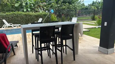 a table with black chairs sitting next to a pool at Villas del sol in Uvita