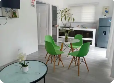 a living room with a table and green chairs at Villas del sol in Uvita