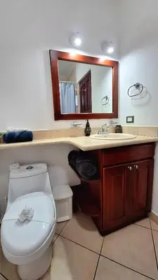 a bathroom with a toilet and a sink and a mirror at 2 beds -2 baths condos near Tamarindo Beach in Tamarindo