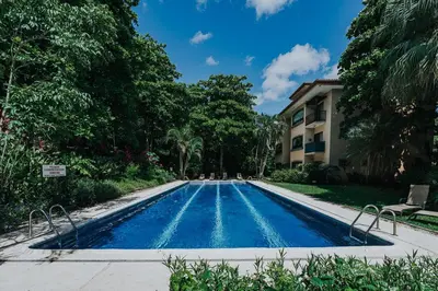 a swimming pool in front of a house with trees at 2 beds -2 baths condos near Tamarindo Beach in Tamarindo