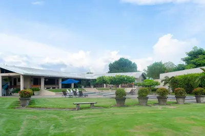 a building with a park with a bench in the grass at Casa Cres, Beachfront, Private Pools, Tennis and AC! in El Roble