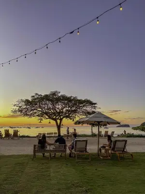 a group of people sitting on benches under an umbrella at Casa Brisa Tranquila, Pools, Gym, & Beach Club in Sardinal