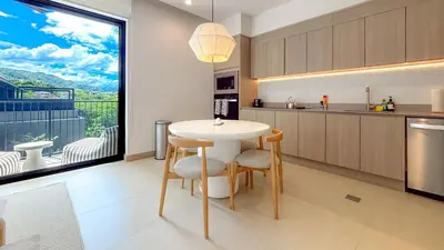 a kitchen with a table and chairs and a large window at Sol Haven at Naumi, Pools, Gym & Beach Club in Sardinal