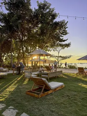 a group of people sitting on lounge chairs in the grass at Sol Haven at Naumi, Pools, Gym & Beach Club in Sardinal
