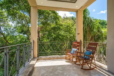 two chairs on a balcony with trees in the background at Beautiful Ocean View Condo Steps to the Beach in Tamarindo