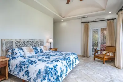 a bedroom with a blue and white bed and a chair at Beautiful Ocean View Condo Steps to the Beach in Tamarindo