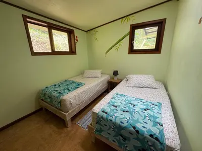 a bedroom with two beds and two windows at Finca Renacer - Jungle Lodges in San Luis