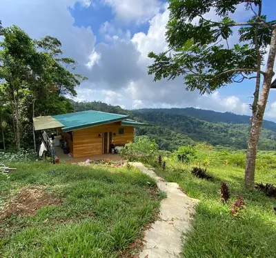 a cabin with a green roof on a hill at Finca Renacer - Jungle Lodges in San Luis