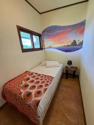 a bedroom with a bed with a painting on the wall at Finca Renacer - Jungle Lodges in San Luis