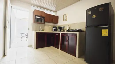 a kitchen with a black refrigerator and wooden cabinets at Casa Sambola in Tortuguero