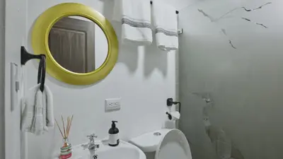 a bathroom with a yellow mirror and a sink at Casa Sambola in Tortuguero