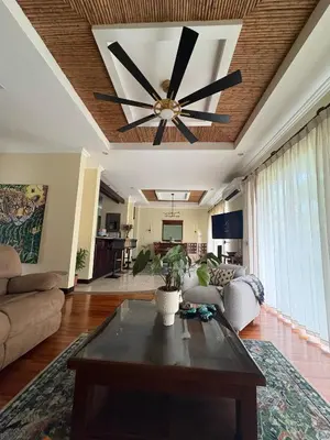 a living room with a ceiling fan and a table at Casa Esperanza Luxury Villa in Esterillos Este