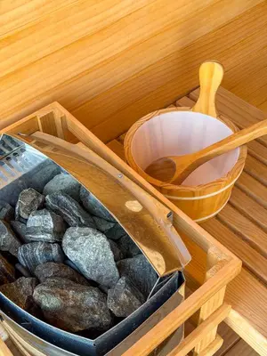 a box of rocks and a wooden spoon in a sauna at Private Wellness Home Sauna, Jacuzzi &Cold Plunge in Brasil