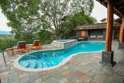 a swimming pool with two chairs and a table at Private Wellness Home Sauna, Jacuzzi &Cold Plunge in Brasil