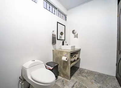 a white bathroom with a toilet and a sink at Casa Azul Tropical Poolside Oasis in Sámara in Sámara