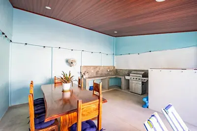 a dining room with a table and a kitchen at Casa Azul Tropical Poolside Oasis in Sámara in Sámara