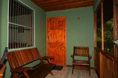 a porch with a rocking chair and a door at Hacienda Baru in Dominical