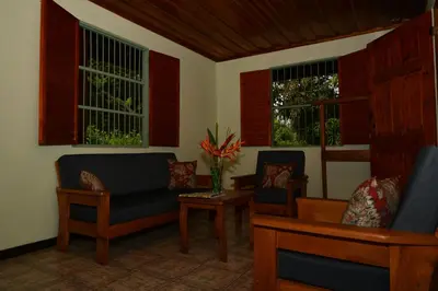 a living room with chairs and a table and windows at Hacienda Baru in Dominical
