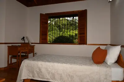 a bedroom with a bed with a window and a desk at Hacienda Baru in Dominical