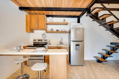 a kitchen with a stainless steel refrigerator and wooden cabinets at 5 Lofts En La Paraiso in Playa Grande