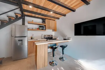 a kitchen with a refrigerator and a counter with stools at 5 Lofts En La Paraiso in Playa Grande