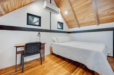 a bedroom with a bed and a desk and a chair at 5 Lofts En La Paraiso in Playa Grande