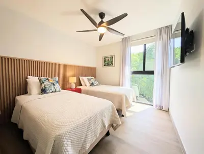 a bedroom with two beds and a ceiling fan at Torres del Mar rainforest-view two-bedroom condo in Jacó