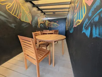 a table and chairs in a restaurant with graffiti on the wall at Torres del Mar rainforest-view two-bedroom condo in Jacó