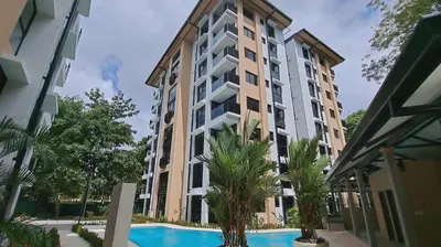 a large apartment building with a swimming pool and palm trees at Torres del Mar rainforest-view two-bedroom condo in Jacó