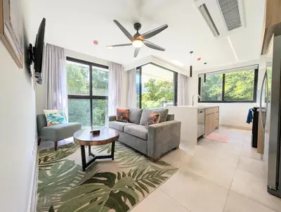 a living room with a couch and a table at Torres del Mar rainforest-view two-bedroom condo in Jacó