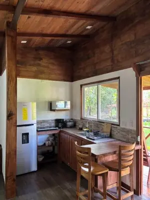 a kitchen with a table and a white refrigerator at Villas El Silencio - Las Tierras de Leonor in San Juanillo