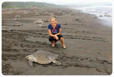 a woman sitting next to a turtle on a beach at Villas El Silencio - Las Tierras de Leonor in San Juanillo