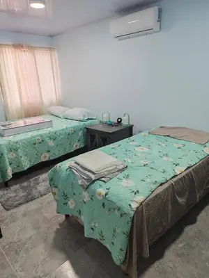 a bedroom with two beds and a table with a bedskirts at Pequeña Casita Karina in Nicoya