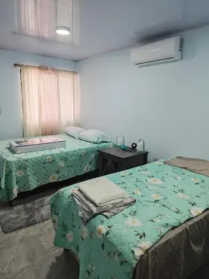 a bedroom with two beds and a table and a window at Pequeña Casita Karina in Nicoya