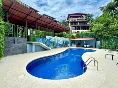 a large blue swimming pool in front of a building at Villas El Parque 18B Central Studio Apartment in Quepos