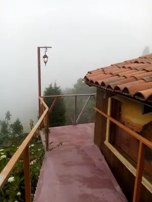 a walkway leading to a building with a foggy view at Lagunillas Del Poas in Poasito