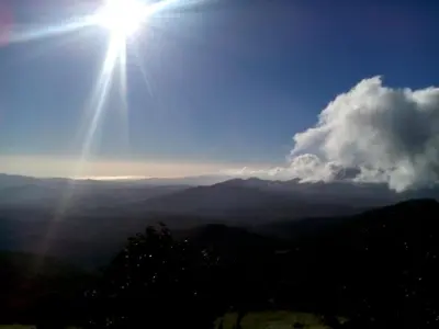 a sun is shining in the sky over the mountains at Lagunillas Del Poas in Poasito