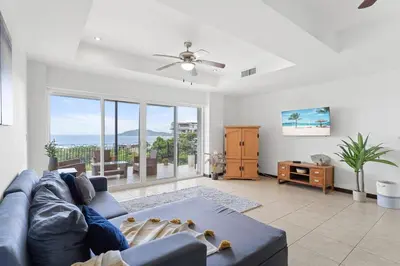 a living room with a blue couch and large windows at Mir3 Tamarindo 2BR Ocean View Retreat in Tamarindo
