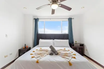 a bedroom with a bed with a fan and a window at Mir3 Tamarindo 2BR Ocean View Retreat in Tamarindo