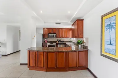 a kitchen with wooden cabinets and a counter top at Mir3 Tamarindo 2BR Ocean View Retreat in Tamarindo