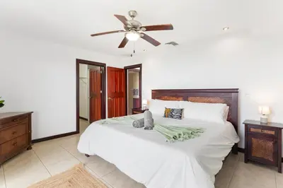 a bedroom with a large white bed with a ceiling fan at Mir3 Tamarindo 2BR Ocean View Retreat in Tamarindo